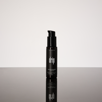Black bottle labeled 'drip water based lubricant' on a reflective surface with a white background