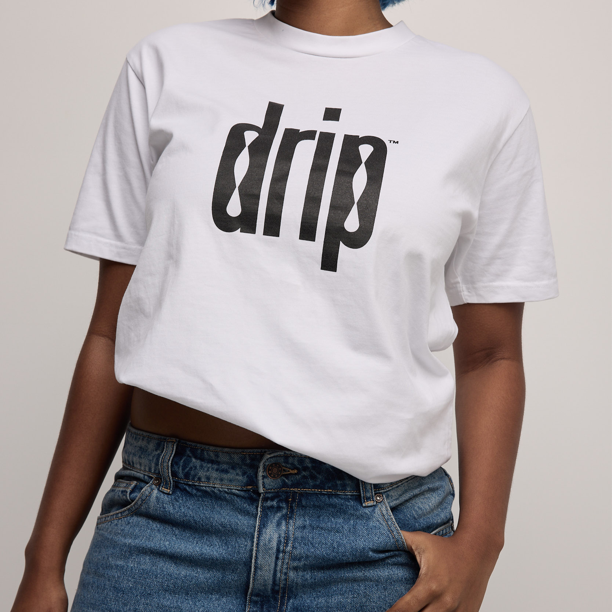 Person wearing a white t-shirt with 'drip' text and blue jeans on a plain background