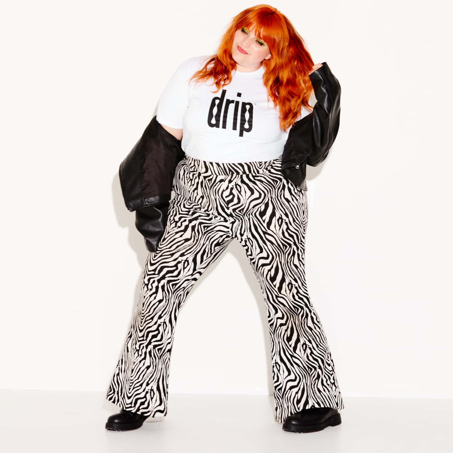 Image of a red-haired woman in a Drip shirt and black and white pants